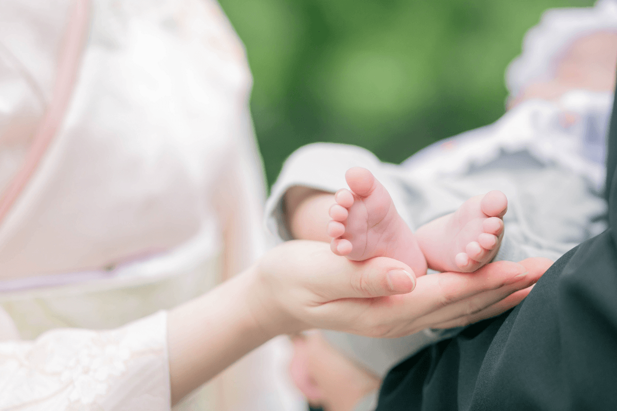 お宮参りで着物を着て赤ちゃんの足を包む夫婦の手
